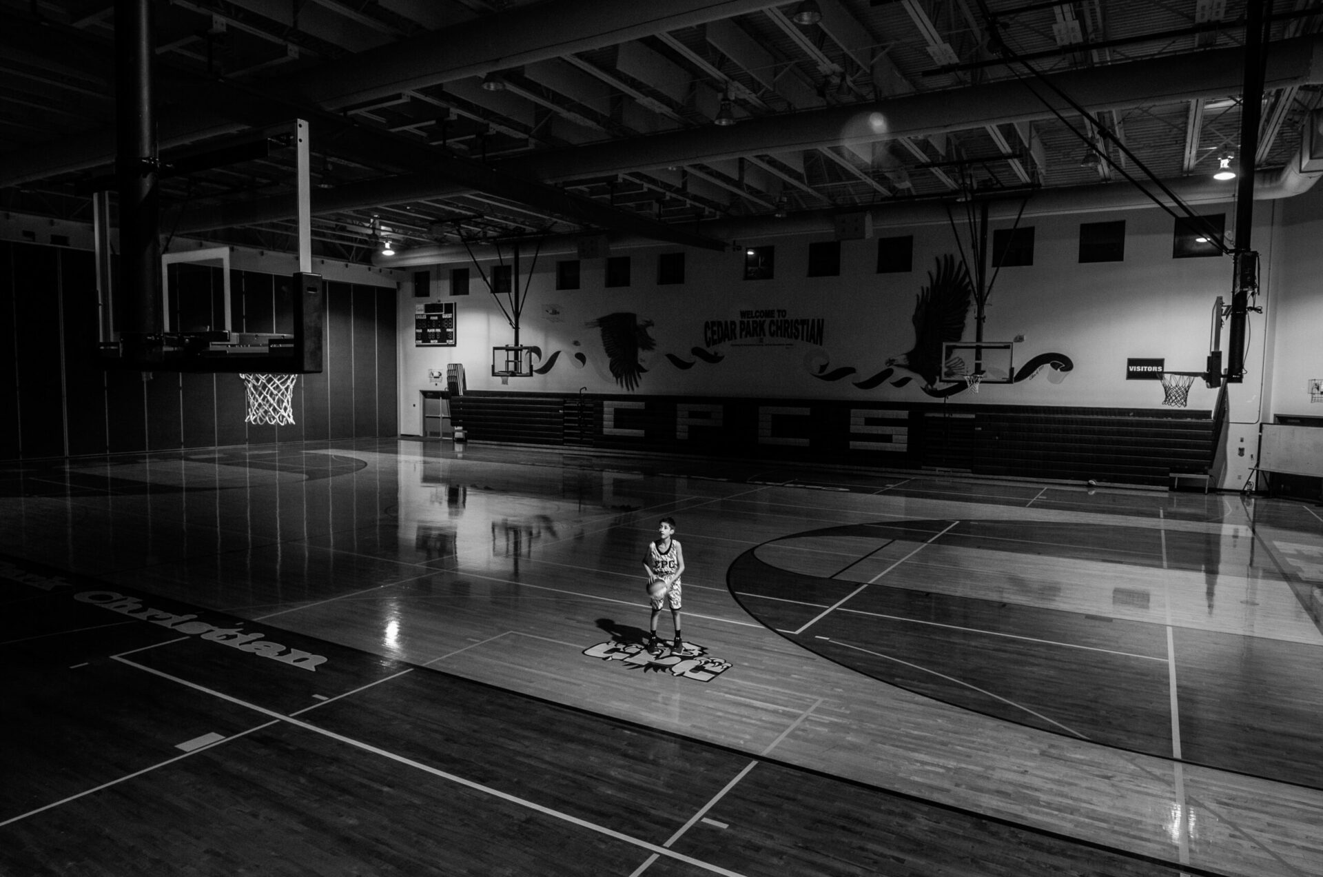 boy playing basketball in empty gym